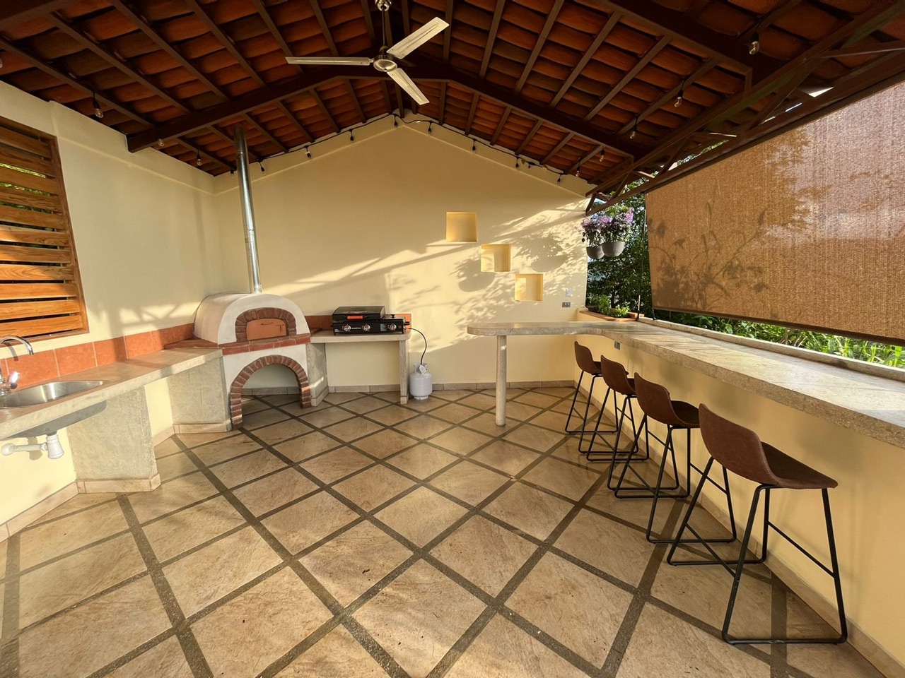 Covered outdoor kitchen with a pizza oven, grill and bar seating